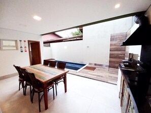 Ein Essbereich mit Holztisch und -stühlen, eine Küche mit Herd und ein kleiner Pool.