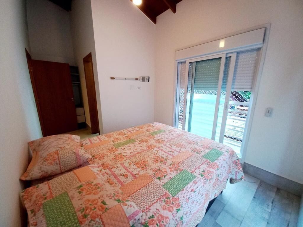 A bedroom with a bed, a window with blinds, and a door to a hallway.