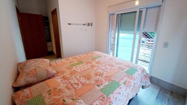A bedroom with a bed, a window with blinds, and a door to a hallway. - House with 3 suites on Juquehy beach. (São Sebastião)