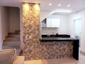 Eine moderne Küche mit geometrischer Wandgestaltung, einer eingebauten Mikrowelle und einer schwarzen Arbeitsplatte.