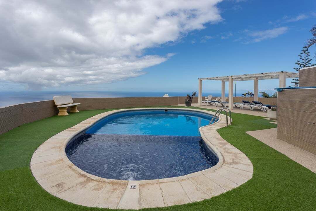 En swimmingpool med havudsigt, omgivet af en terrasse med liggestole.