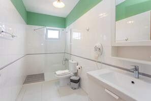 Et badeværelse med brusebad, toilet og håndvask.