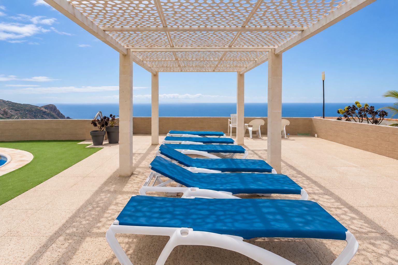 Un espacio al aire libre techado con sillones de descanso y una piscina.