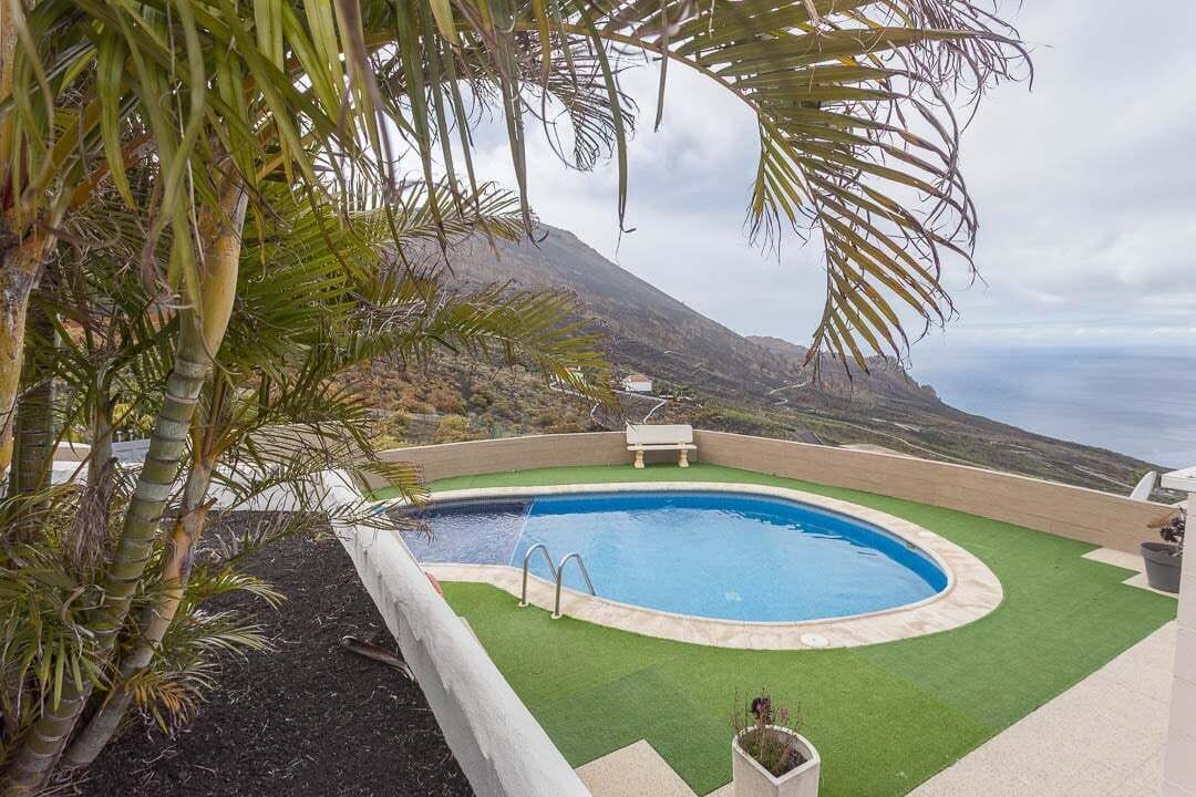 Una piscina con vista al océano y una montaña al fondo.