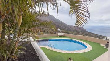 Una piscina con vista al océano y una montaña al fondo.