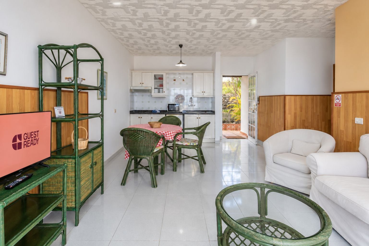 Una habitación con comedor, televisor y sofá blanco.