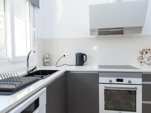 Eine moderne Küche mit Spüle aus Edelstahl, Wasserkocher und Backofen.