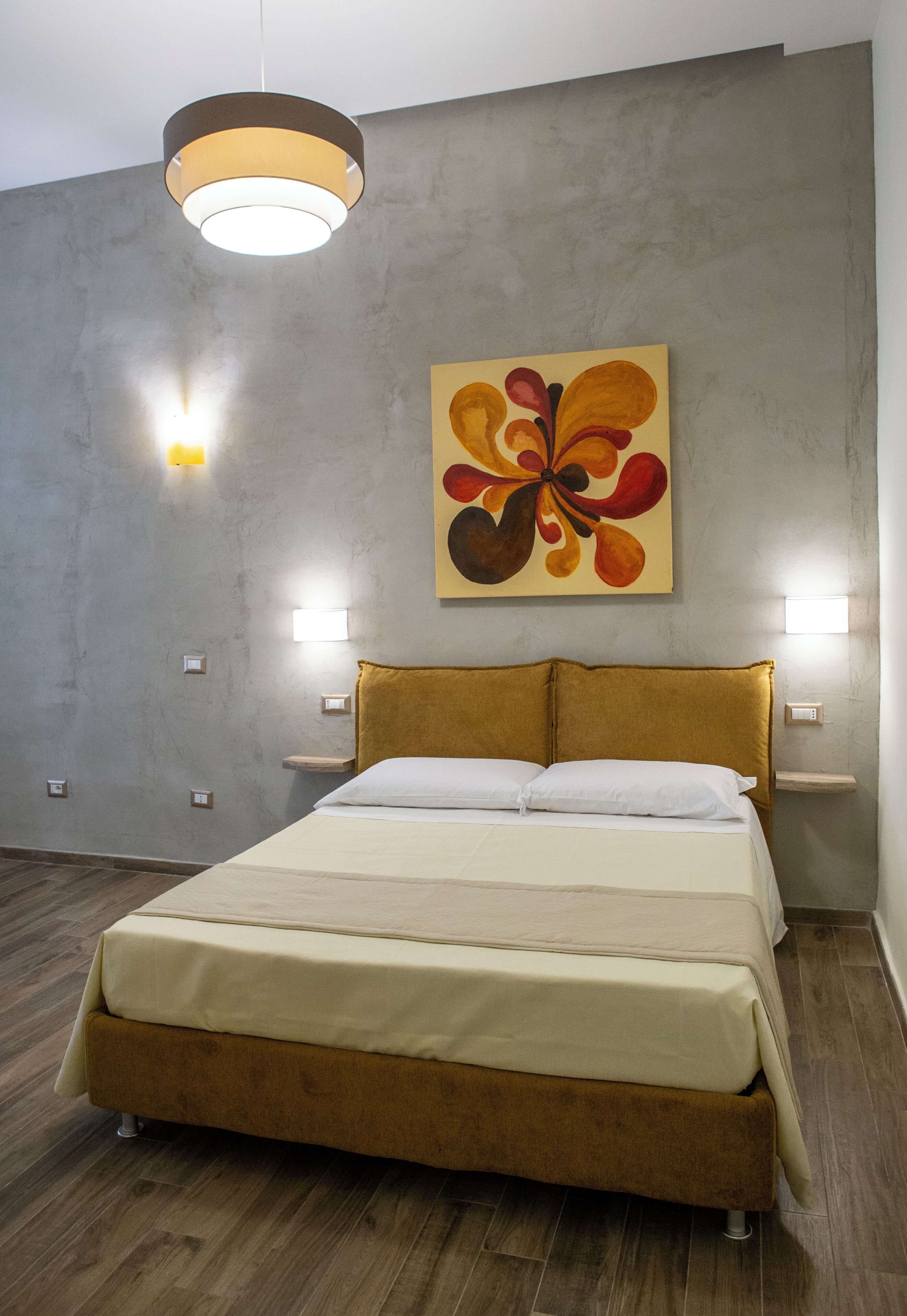 Une chambre moderne avec un grand lit, un tableau abstrait accroché au mur et deux lampes de chevet.