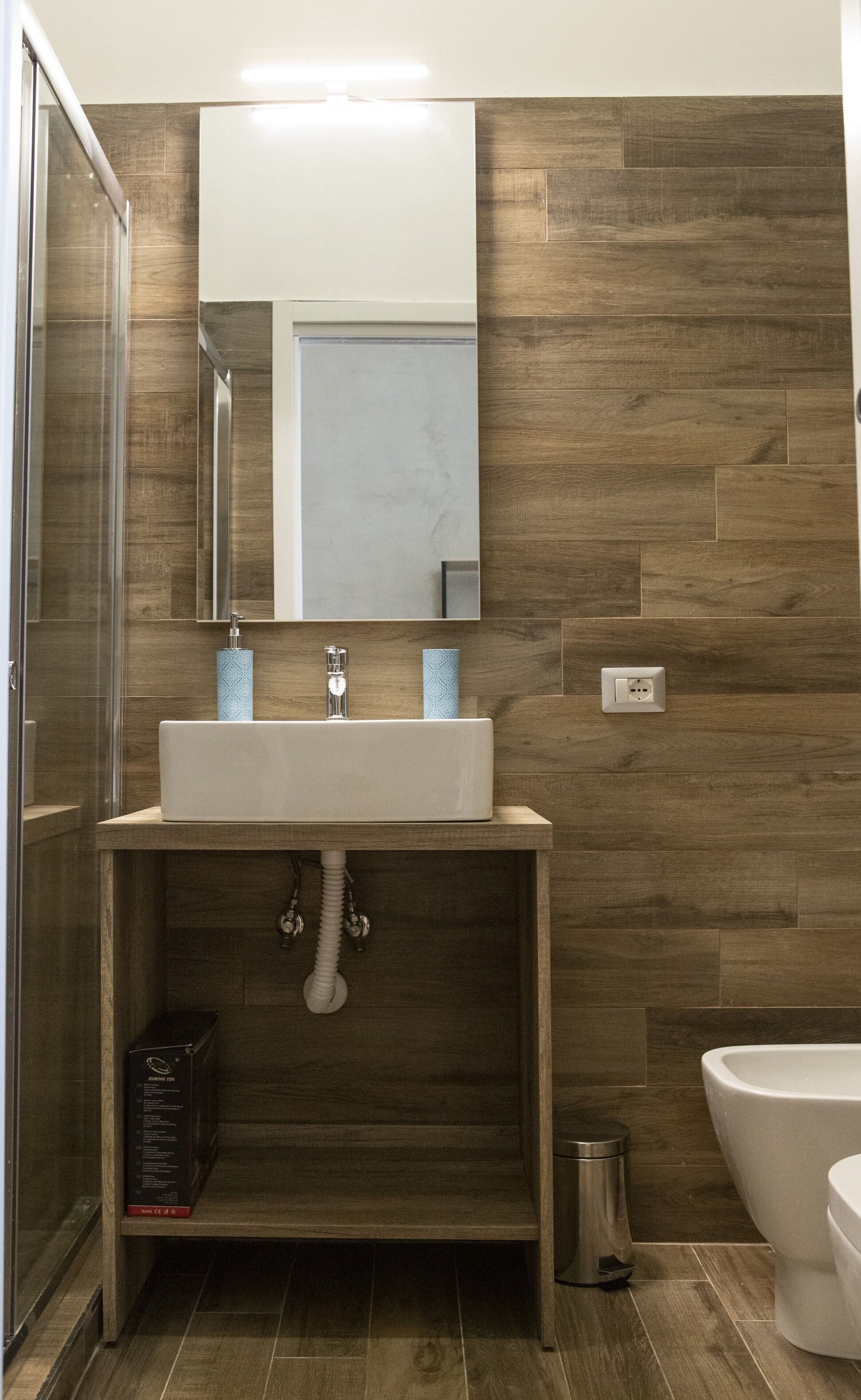 Une salle de bain avec un meuble-lavabo en bois, un miroir, un lavabo et des toilettes.
