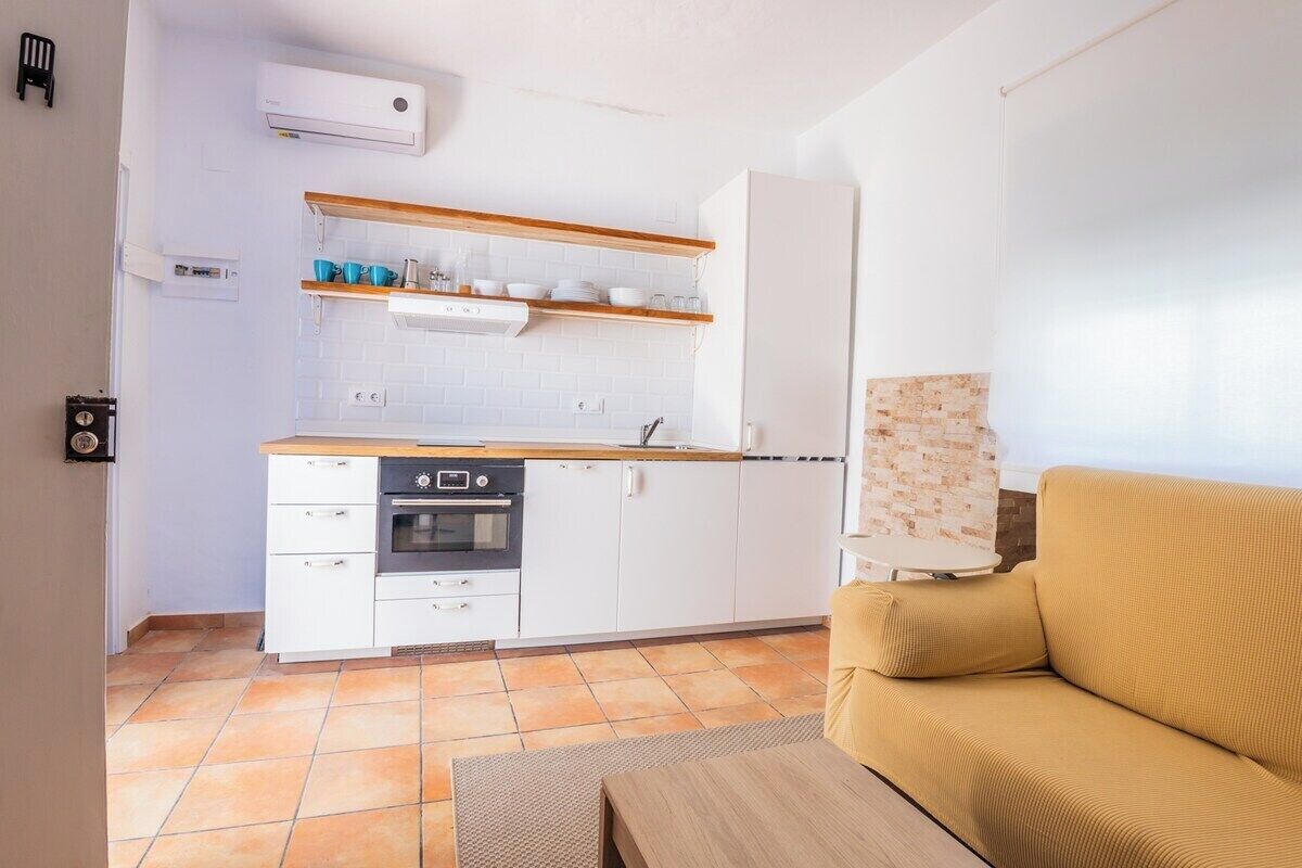 A compact kitchen with white cabinets, a wooden countertop, and a built-in oven.