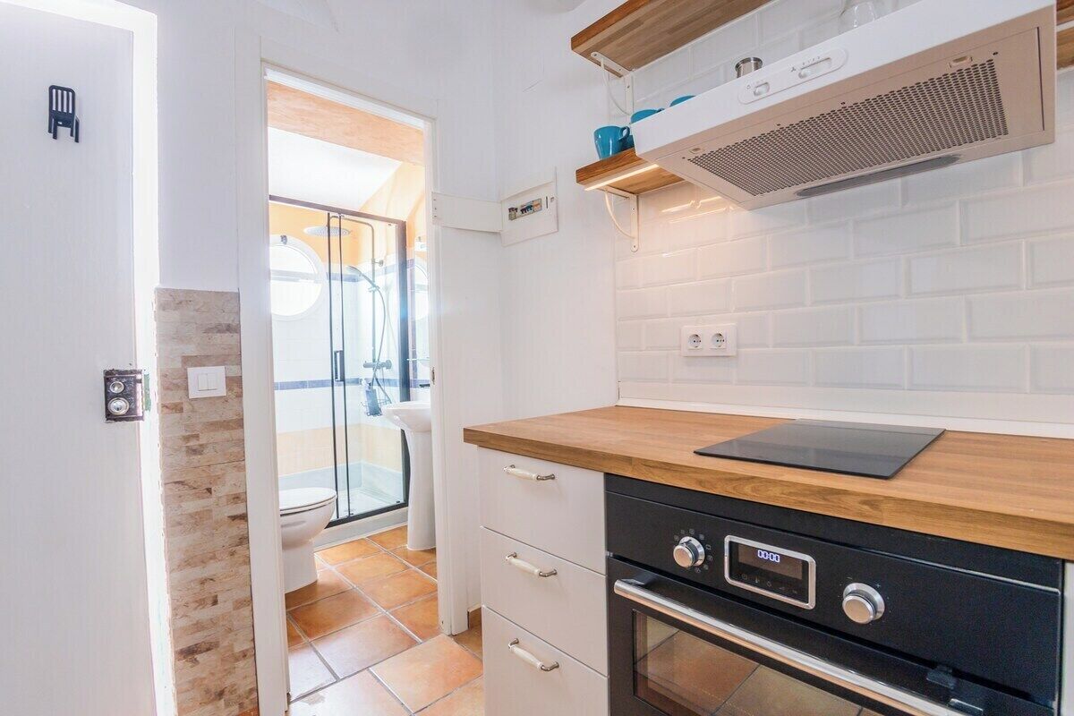 Une cuisine moderne dotée d’un plan de travail en bois, d’un four encastré et d’un dosseret de carrelage blanc.