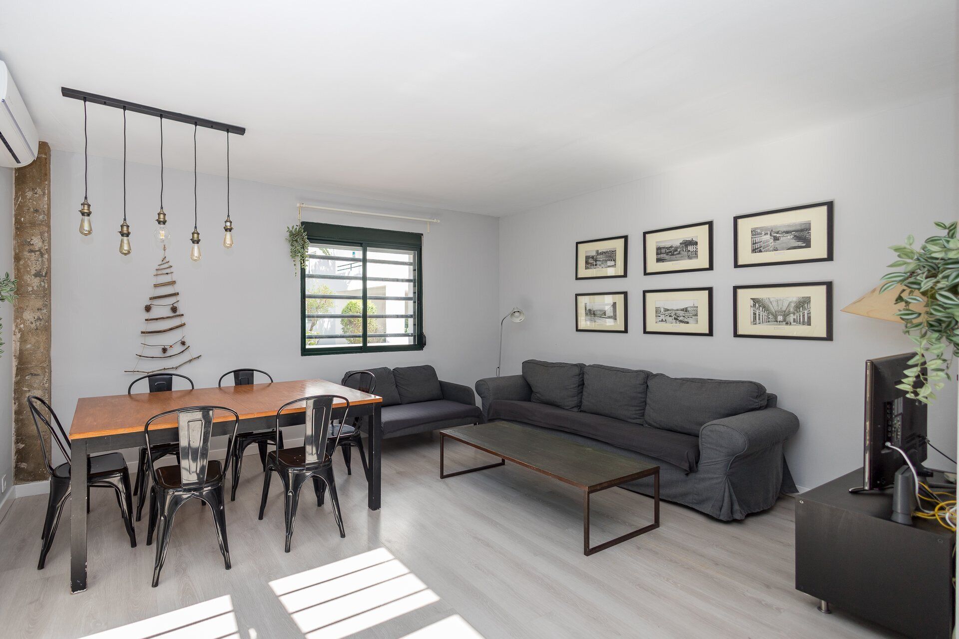 A modern living space with a dining table, chairs, a sofa, a coffee table, and a TV.