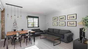 Un espacio habitable moderno con una mesa de comedor, sillas, un sofá, una mesa baja y un televisor.