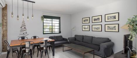 A modern living space with a dining table, chairs, a sofa, a coffee table, and a TV.