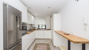 Una cocina moderna con electrodomésticos de acero inoxidable, una encimera de madera y una alfombra estampada.