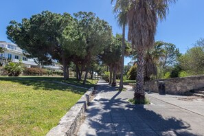 A pathway lined with trees and a stone wall, leading to a building with a white facade. - GuestReady - Ancora terraza y piscina (El Puerto de Santa María)