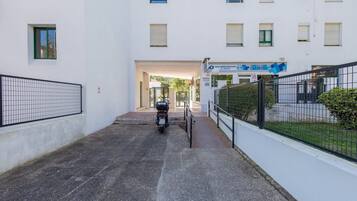 Un estrecho callejón que conduce a una entrada con puerta y una motocicleta estacionada en el centro.