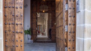 Una puerta de madera con remaches metálicos, que da paso a un interior de paredes de piedra.