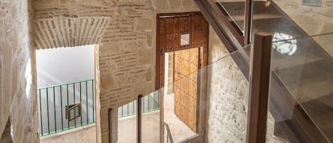 A staircase with a glass railing leading to a wooden door with metal studs.
