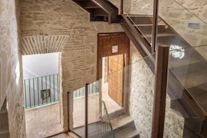 Eine Treppe mit Glasgeländer, das zu einer Holztür mit Metallbeschlägen führt.