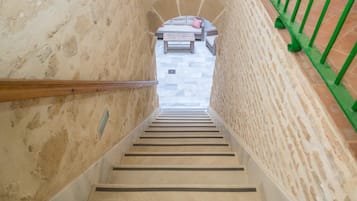 A staircase with a wooden handrail leading to a seating area with a bench and cushions.