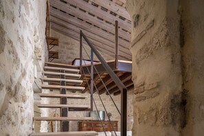 Ein rustikaler Innenraum mit freiliegenden Backsteinwänden, einer Holztreppe und einem schlichten Holzschrank.