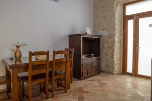 Un comedor con una mesa y sillas de madera, un armario y un piso de baldosas.