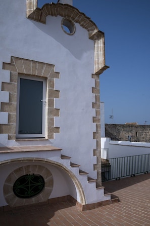 Ein Gebäude mit heller Fassade, einem Rundfenster und einer Steintreppe, die zu einer Tür führt.