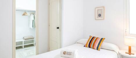 A hotel room with a bed, a bedside table with a lamp, a wardrobe, and a ceiling fan.