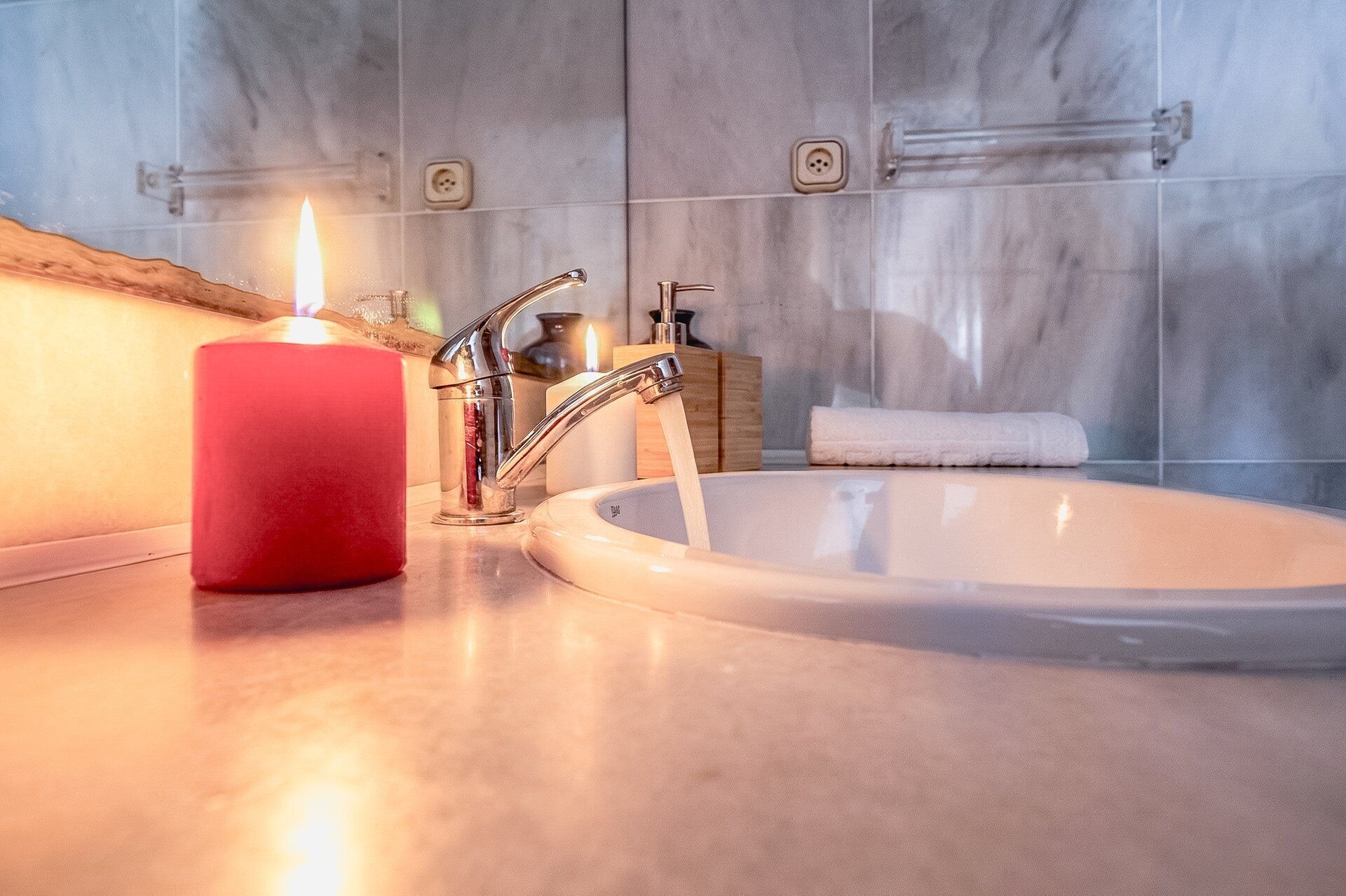 Un baño con lavamanos, una vela roja y una toalla.