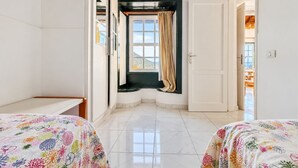 Ein Hotelzimmer mit zwei Betten, einem Vorhangfenster, einer Tür und Blick ins Freie.