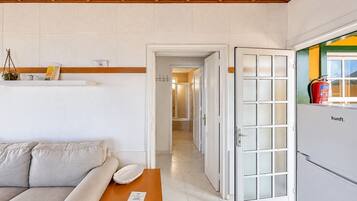 Una sala de estar con un sofá, una mesa y una puerta que da a un pasillo.