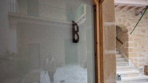 Una puerta de vidrio con la letra 'B', que da a una escalera de piedra y un espacio con suelo de baldosas.