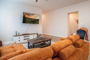 Een woonkamer met een bank, een salontafel en een aan de muur bevestigde televisie.