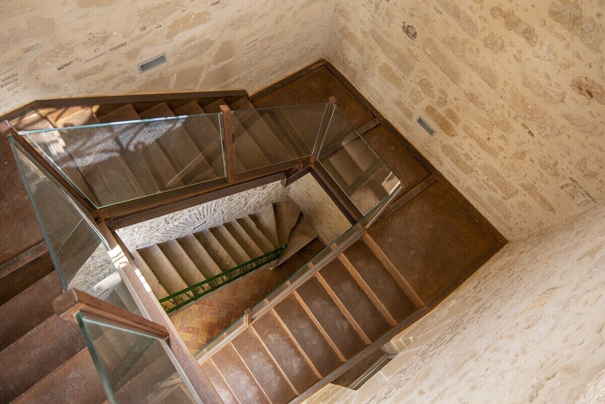 Eine Wendeltreppe mit Glasgeländern und einer Steinwand.
