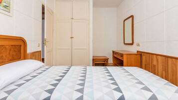 Un dormitorio con una cama, un aparador de madera, una mesita y un armario.