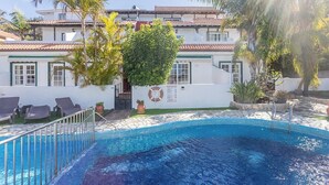 A swimming pool with a tiled edge, surrounded by lounge chairs and palm trees, with a building in the background. - GuestReady - Colon I 9 2 pax (Los Quemados)