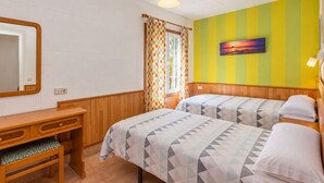 A room with two beds, a wooden desk, a mirror, and a window with curtains. - GuestReady - Colon I 9 2 pax (Los Quemados)