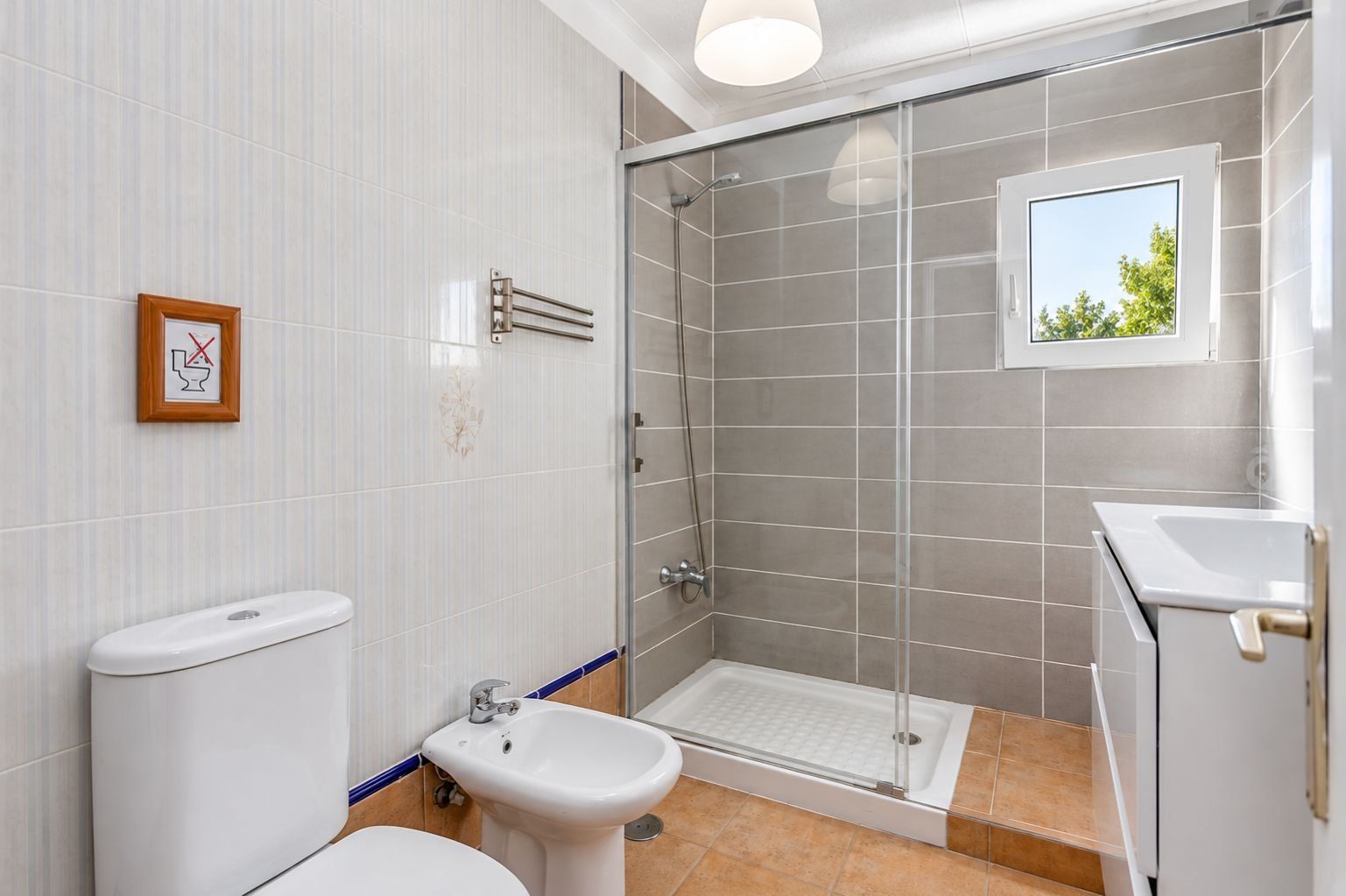 Un baño moderno con cabina de ducha de vidrio, inodoro, bidé y lavamanos.