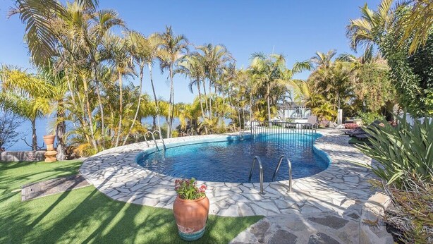 A pool surrounded by palm trees and a stone deck. - GuestReady - Colon I 9 2 pax (Los Quemados)