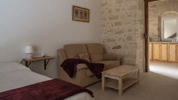 A bedroom with a bed, a sofa, a small table, and a nightstand with a lamp. - GuestReady - La Cruz 2D (El Puerto de Santa María)