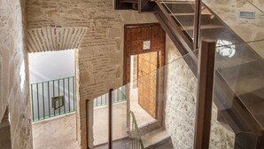 A modern interior with a staircase, a wooden door, and a view of the outside. - GuestReady - La Cruz 2D (El Puerto de Santa María)