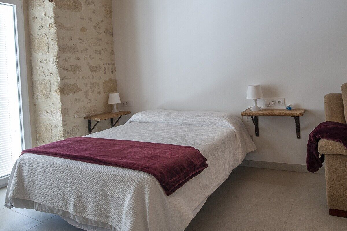 Een slaapkamer met een bed, twee nachtkastjes, een lamp en een stoel.