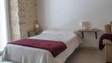 Een slaapkamer met een bed, twee nachtkastjes, een lamp en een stoel.