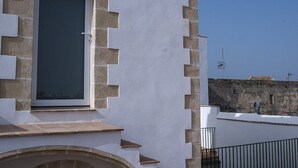 A building with a white facade, a circular window, and a door with a window. - GuestReady - La Cruz 2D (El Puerto de Santa María)