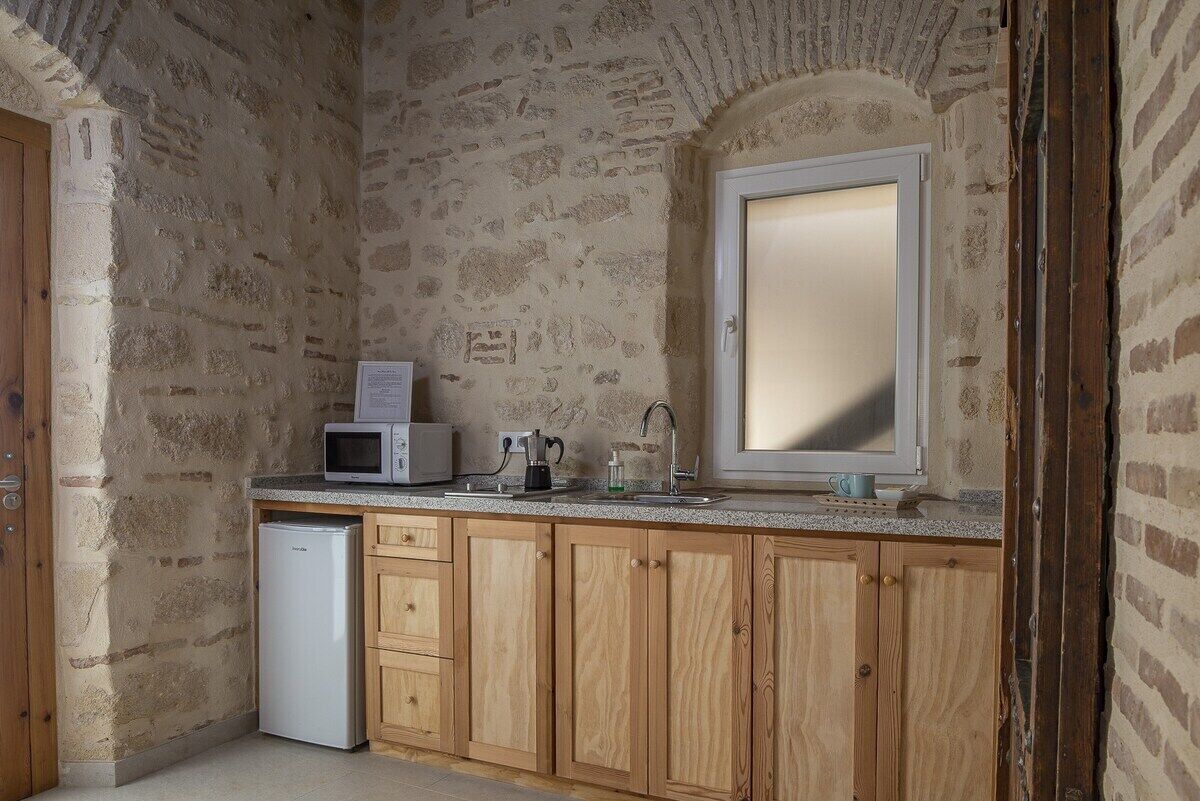 A compact kitchen with a stone wall, a microwave, a coffee maker, and a sink.