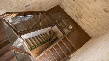A spiral staircase with glass railings and a stone wall.