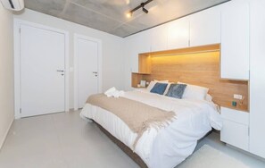 A bedroom with a bed, bedside tables, a wardrobe, and a ceiling light fixture. - Corporate Stays First del Sol - 103 (Asunción)