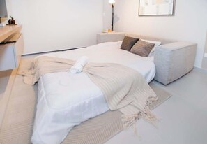 A modern bedroom with a bed, bedside tables, and a lamp. - Corporate Stays First del Sol - 103 (Asunción)
