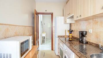 Una cocina compacta equipada con microondas, lavadora y cafetera.